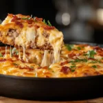 A serving of cowboy cornbread casserole being lifted from a skillet.