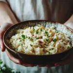 A bowl of French onion rice topped with melted cheese and crispy onions.